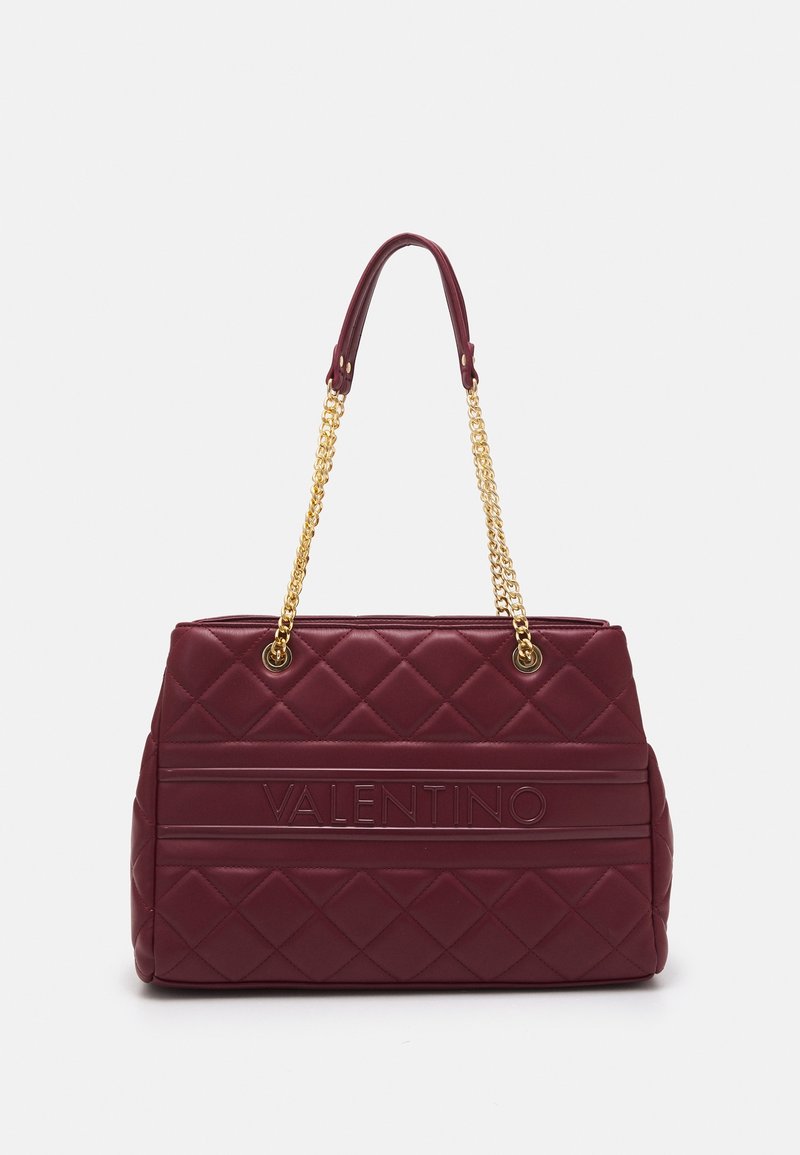Maroon quilted handbag with gold chain straps. Features embossed logo and rectangular design. Smooth texture with a structured silhouette.
