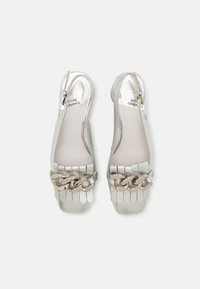 Metalliset hopeiset slingback-kengät, joissa on litteä muotoilu, poimutettu yksityiskohta ja näyttävä kultaketjuetuosa. Sujuva pinta.