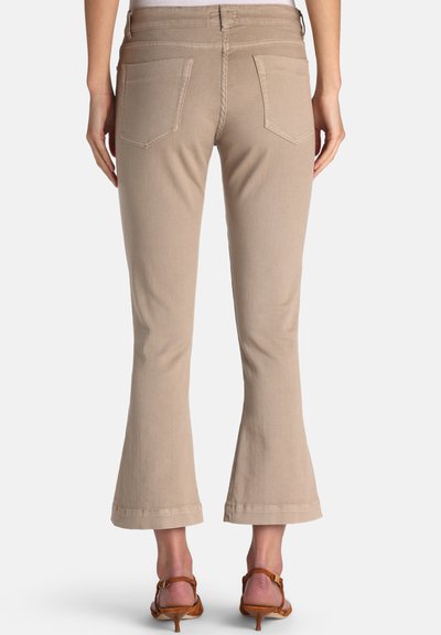 Bež razširjene kavbojke z teksturirano tkanino, dvema zadnjima žepoma in zavihanim robom, v kombinaciji z rjavimi sandali na peto.