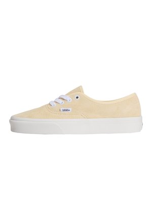 Baskets basses Vans beige en daim avec semelle en caoutchouc blanche et lacets blancs, vues de profil sur fond blanc.