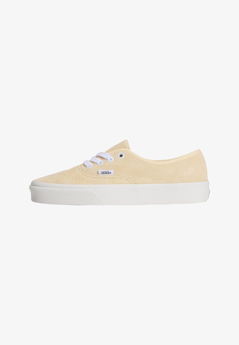 Baskets basses Vans beige en daim avec semelle en caoutchouc blanche et lacets blancs, vues de profil sur fond blanc.