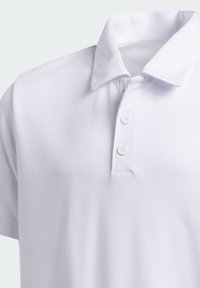 Biała koszulka polo z krótkim rękawem, z zapięciem na kołnierzyk i dwiema białymi guzikami na plisce.