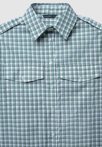Camicia a quadri verde e bianca, con colletto button-down, due tasche sul petto e bottoni chiari. Realizzata in tessuto leggero.