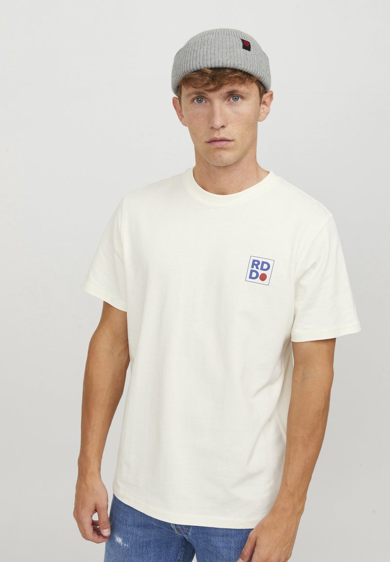 Weißes Baumwoll-T-Shirt mit rundem Halsausschnitt, kurzen Ärmeln und einem blau-roten rechteckigen Logo auf der linken Brust. Lässige Passform, simples Design.