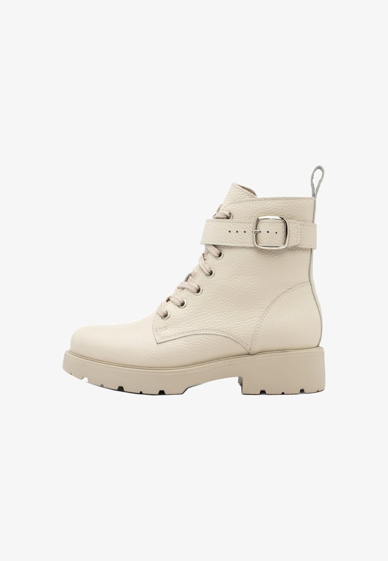 Bež nahkasaapad, millel on nööpimisega esitükk, lapik tald ja pandla rihm ümber pahkluu. Tekstureeritud pind ja pehmendusega kaelus.