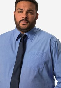 Lichtblauw geknoopte shirt met een borstzak en textuurstof, gecombineerd met een donkerblauwe das. Professioneel ontwerp, ontspannen pasvorm.