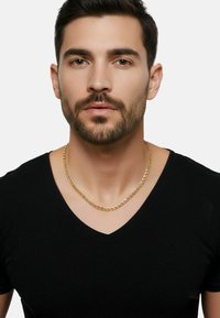 Gouden ketting met in elkaar grijpende schakels, gedragen over een zwarte V-hals T-shirt, met een gladde textuur en een gepolijste afwerking.