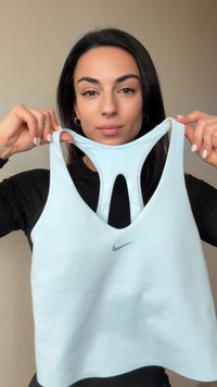 Lyseblå sports-bh lavet af elastisk stof, med et cut-out design og en lille Nike-logo foran. Justerbare stropper giver støtte.