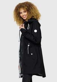 Black waterproof parka with white accents, adjustable hood, drawstring waist, and snap pockets. Smooth textured fabric, mid-length design.