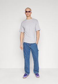 Tricou gri cu mânecă scurtă, blugi albaștri drepti, pantofi sport violeți și ochelari de soare violeți. Design simplu, look casual și potrivire lejeră.