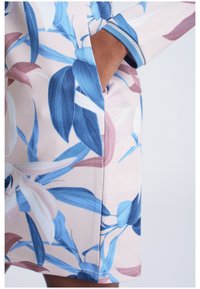 Robe fleurie avec un fond rose clair orné de grandes feuilles bleues et roses, manches courtes et poche latérale. Tissu lisse et extensible.