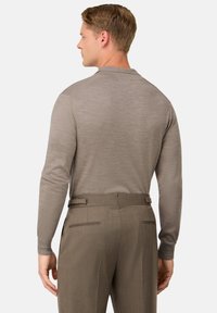 Světle šedá košile s dlouhými rukávy z jemné tkaniny s jemnou texturou, nošená s tmavě šedými kalhotami se zadními kapsami a poutky na opasek.