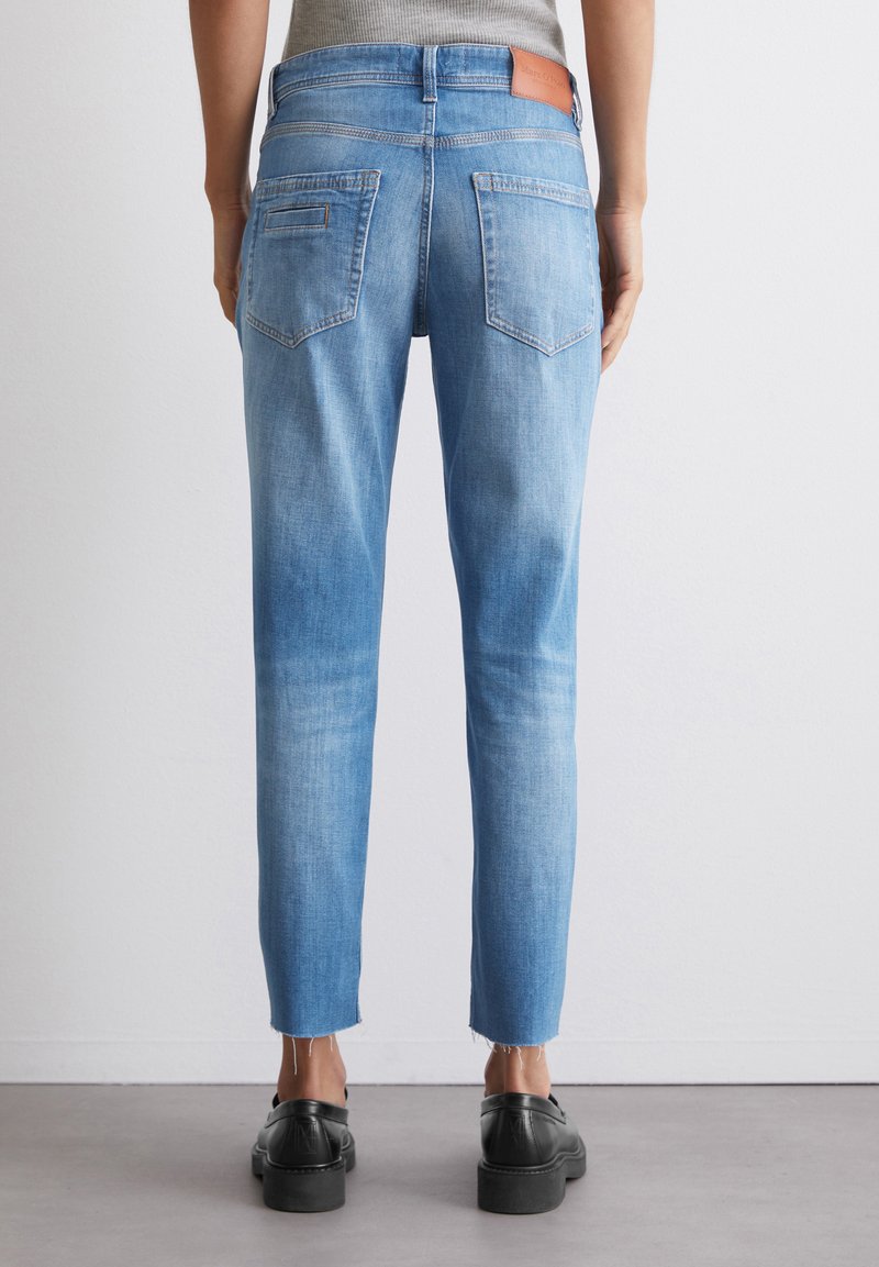 Hellblaue Jeans aus Denim mit schmalem Schnitt, mittelhoher Taille, Gesäßtaschen und rohen Säumen. Verfügt über ein Lederetikett auf der Rückseite.