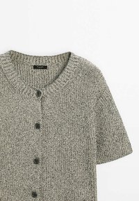 Cardigan en maille à manches courtes avec encolure ronde et quatre boutons noirs, tissu en fil gris et blanc texturé.