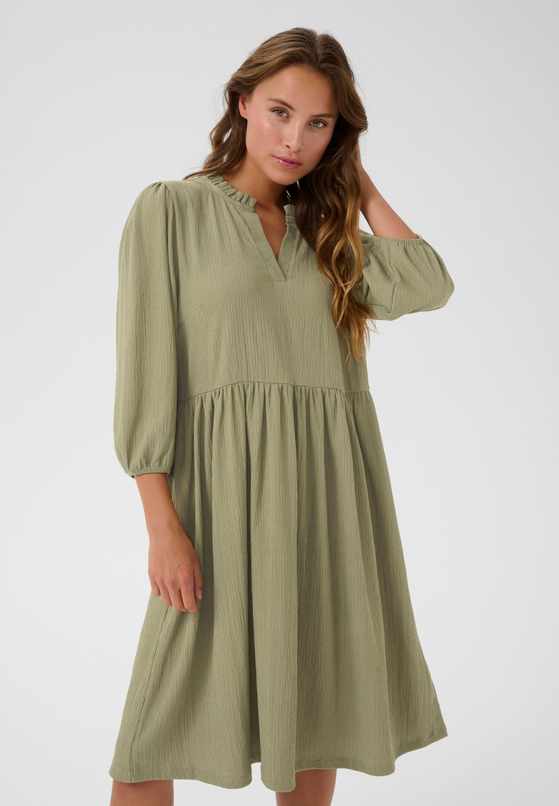 Grünes, strukturiertes Kleid mit V-Ausschnitt und Rüschensaum, dreiviertellangen Puffärmeln und einem fließenden, gestuften Rockdesign.