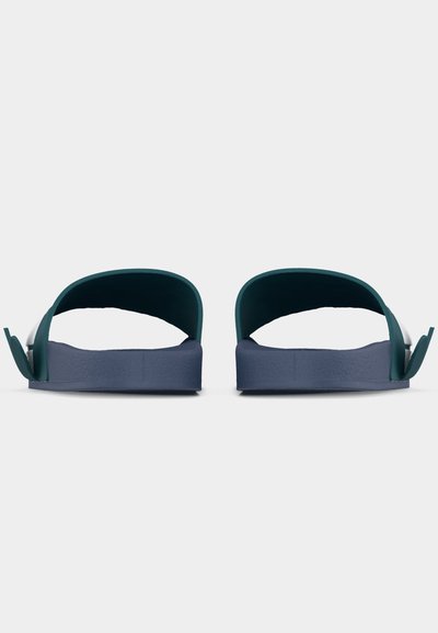Ζευγάρι μπλε σανδαλιών με πλατιά λουριά και υφασμένα πέλματα, εμφανιζόμενα από πίσω σε λευκό φόντο.