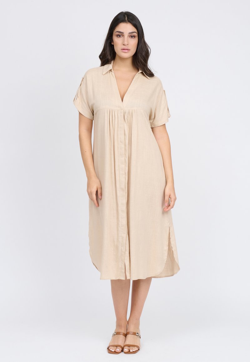 Abito beige leggero, con maniche corte, colletto, scollatura a V, bottoni nascosti e spacco sui lati. Tessuto morbido. Design casual.