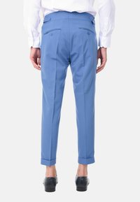 Pantaloni azzurri chiari con vestibilità su misura, caratterizzati da una vita piana, doppie tasche posteriori e orli arrotolati; realizzati in tessuto morbido.