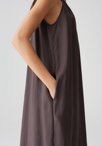 Ärmelloses, dunkelbraunes Kleid aus glattem Stoff, mit Seitentaschen und lockerer Passform. Verfügt über einen runden Ausschnitt und einen dezenten Glanz.