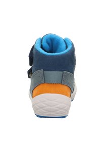 Modrá a šedá semišová bota s oranžovým akcentem, suchým zipem a bílou gumovou podrážkou. Měkká podšívka je viditelná na horním okraji.