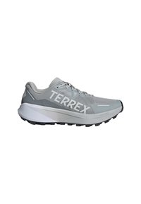Zapatilla deportiva gris claro con parte superior de malla, diseño texturizado, destacada marca "TERREX" en blanco y suela de goma negra con tracción.