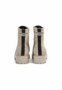 Stivaletti in suede beige con una striscia laterale nera, chiusura a cerniera e suole spesse caratterizzate da un motivo testurizzato e logo in rilievo.
