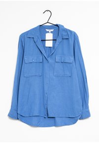 Camisa azul de manga larga hecha de tejido ligero, con collar, cierre de botones en la parte delantera y dos bolsillos en el pecho con solapas.