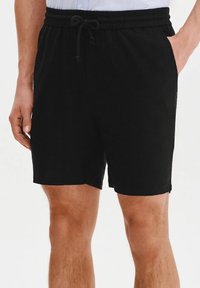 Czarne szorty wykonane z miękkiego materiału, z elastycznym pasem, zaciągnięciem na sznurku i bocznymi kieszeniami dla wygody.