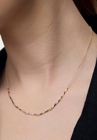 Złoty naszyjnik z wydłużonymi, skręconymi ogniwami o polerowanym wykończeniu. Łańcuszek jest delikatny i pięknie podkreśla linię szyi.