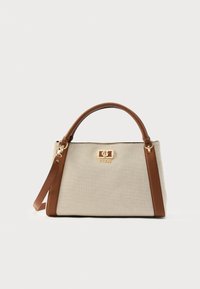 Borsa in tessuto beige con manici e rifiniture in pelle marrone, logo GUESS dorato e tracolla removibile su sfondo bianco.