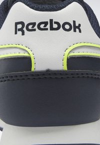 Navyblå och vit sneakerskonk med texturerad ovandel, med gula detaljer och svart "Reebok"-logotyp. Slätt, hållbart material.