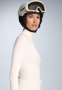 Witte thermoshirt met lange mouwen en een gestructureerd patroon, gecombineerd met een zwarte skihand met een gladde vizier en verstelbare banden.