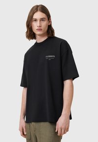 Zwarte katoenen T-shirt met korte mouwen, ronde hals en een logo in tekst aan de voorkant. Casual pasvorm met een zachte textuur en zonder zichtbare patronen.