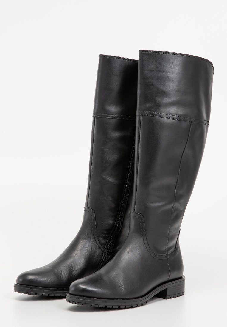 Hohe schwarze Lederstiefel mit niedrigen Absätzen, runder Spitze und seitlichen Reißverschlüssen, die aufrecht vor einem weißen Hintergrund stehen.