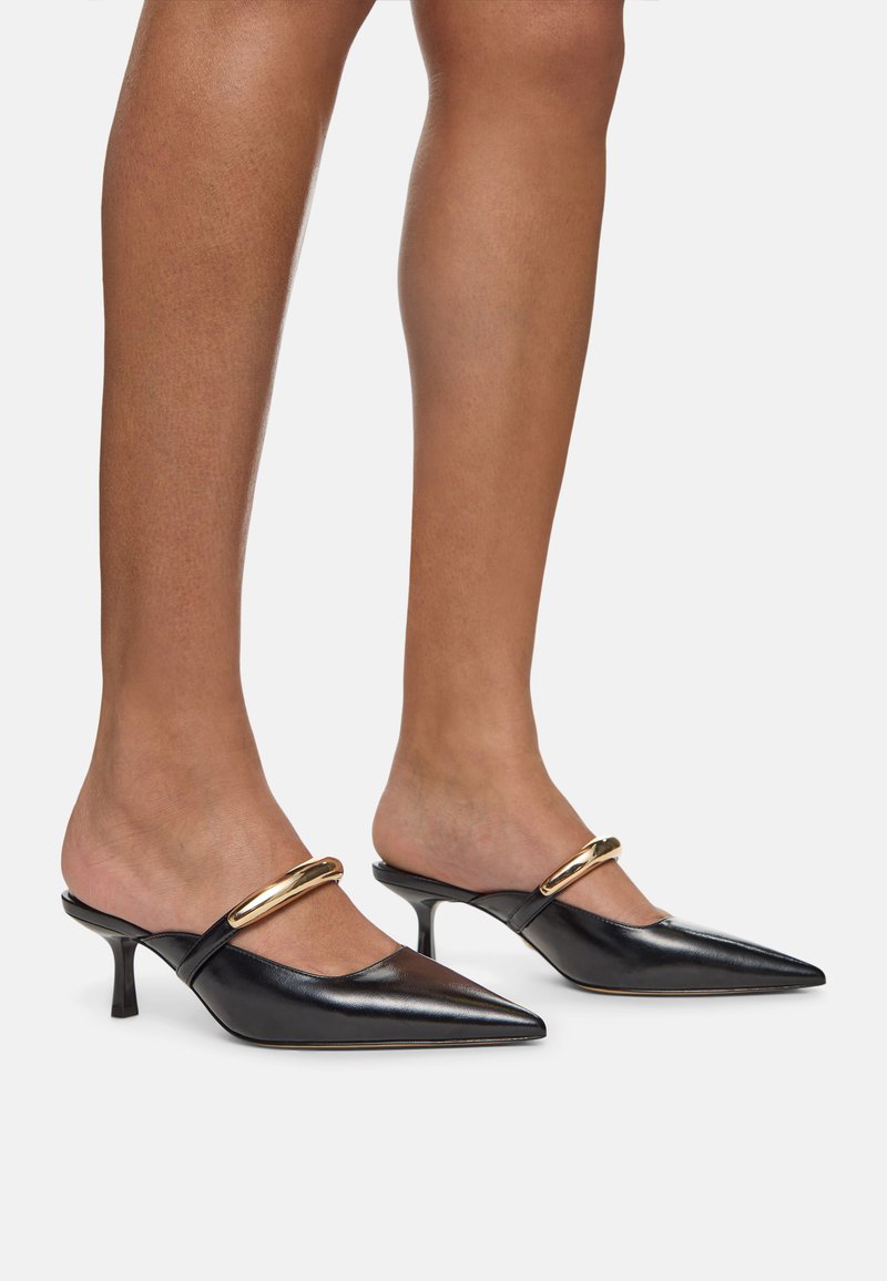 Svarta lädersandaler med spetsiga tår, som har en smal guldkant och en kort, tunn klack för modern elegans.
