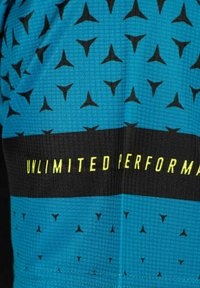 Tejido atlético azul con un patrón de cuadrícula. Motivos triangulares negros por todo el diseño. Una franja negra con "RENDIMIENTO ILIMITADO" en texto amarillo.