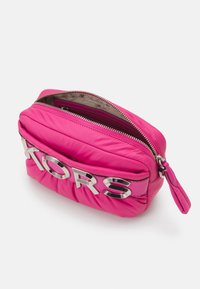 Wypchana różowa kosmetyczka z metalowymi elementami w kolorze srebrnym i logo, z zamkiem błyskawicznym oraz fakturowanym wzorem na powierzchni.