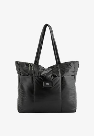 Black quilted tote bag with two long handles, featuring a rectangular patch label on the front and colorful accent drawstrings.