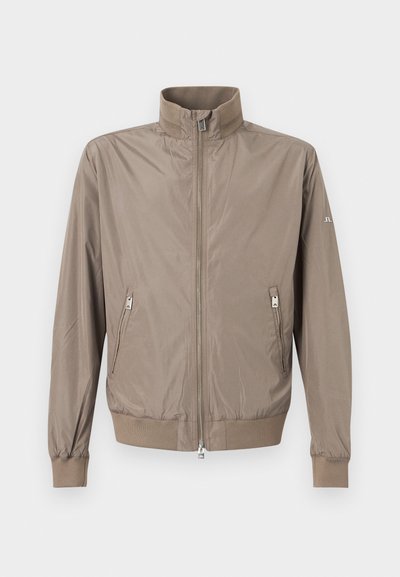 Ανοιχτό καφέ μπουφάν με φερμουάρ και όρθιο γιακά, δύο εμπρόσθιες τσέπες με φερμουάρ, ριμπ μανσέτες και στρίφωμα, σε απλό φόντο.