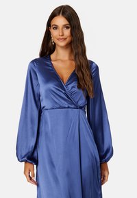 Sukienka z długim rękawem, głębokim dekoltem w kształcie V w bogatym niebieskim satynie, z fasonem typu wrap i zwiewną spódnicą, o miękkiej strukturze i dopasowanym topie.