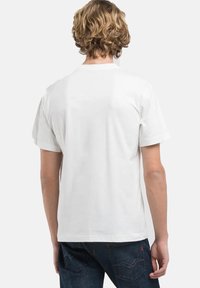 Witte katoenen t-shirt met korte mouwen, rechte snit en een minimalistisch ontwerp. De achterkant heeft een gladde textuur zonder grafische elementen of accenten.