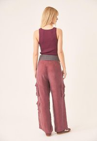 Top de tirantes acanalado en color marrón, combinado con pantalones cargo de pierna ancha en una tela suave y texturizada. Los pantalones cuentan con múltiples bolsillos y un corte relajado.