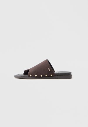 Sort ruskindssandal med åben tå, guldnitteaccenter langs den ydre kant og en flad gummisål.