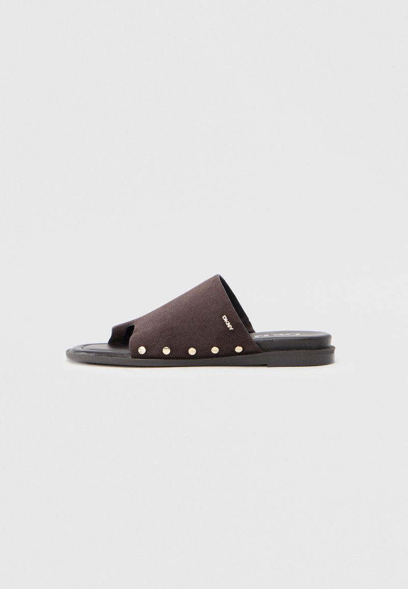 Sandale mule en daim noir avec bout ouvert, ornée de clous dorés le long du bord extérieur, et semelle plate en caoutchouc.