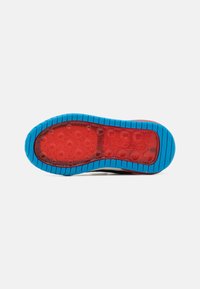 Shoe outsole features a red rubber base with blue textured traction pattern. The design includes circular grip points for improved stability.