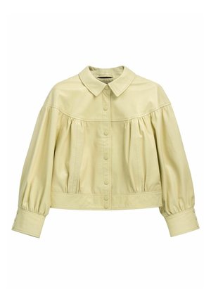 Jasnobeżowa kurtka z eko skóry z przodu na guziki, marszczonym karczkiem, bufiastymi długimi rękawami oraz szerokimi mankietami z guzikami.