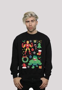 Crna dukserica s nasmijanom šarenom karikaturom Iron Mana i Hulka, uz božićne simbole poput božićnog drvca, poklona i ukrasa.