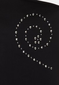 Clous argentés circulaires et en forme de pyramide disposés en spirale sur un tissu noir.