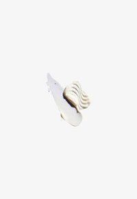Crema blanca con una textura suave, con un patrón ondulado. Se extiende sobre una superficie clara y reflectante, creando sombras sutiles.