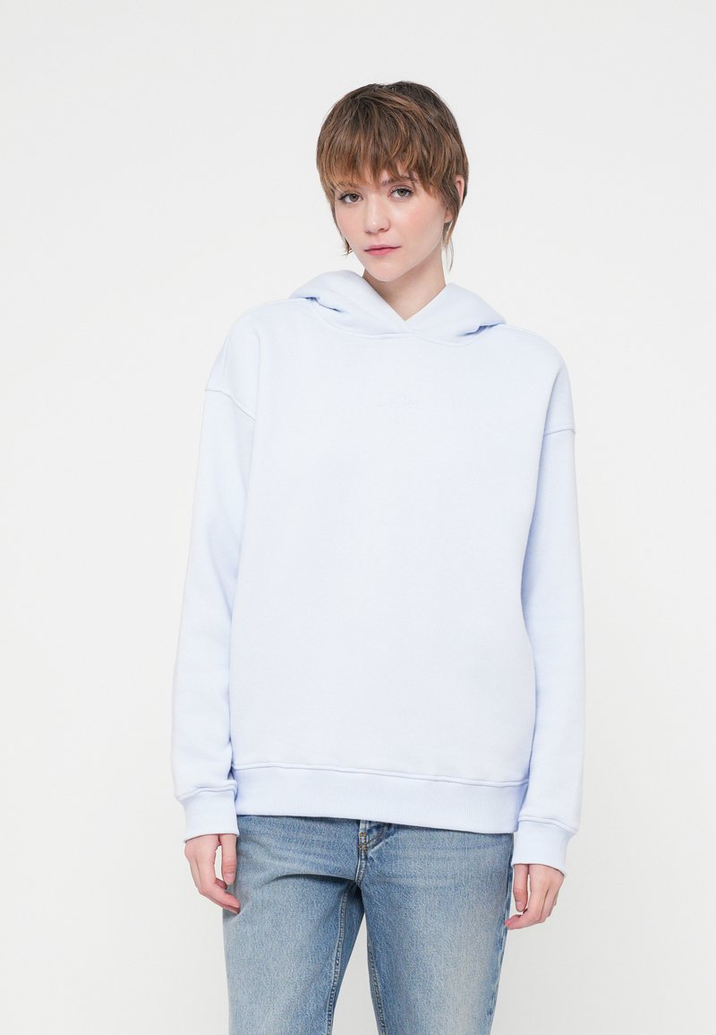 Hanorac bleu deschis dintr-un amestec moale de bumbac, dotat cu glugă cu șnur și manșete ribbate, asortat cu blugi pentru un look casual.